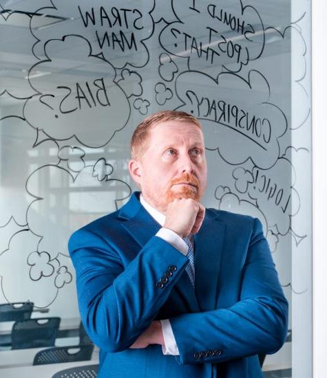 A professor st和s pondering in front of glass whiteboard